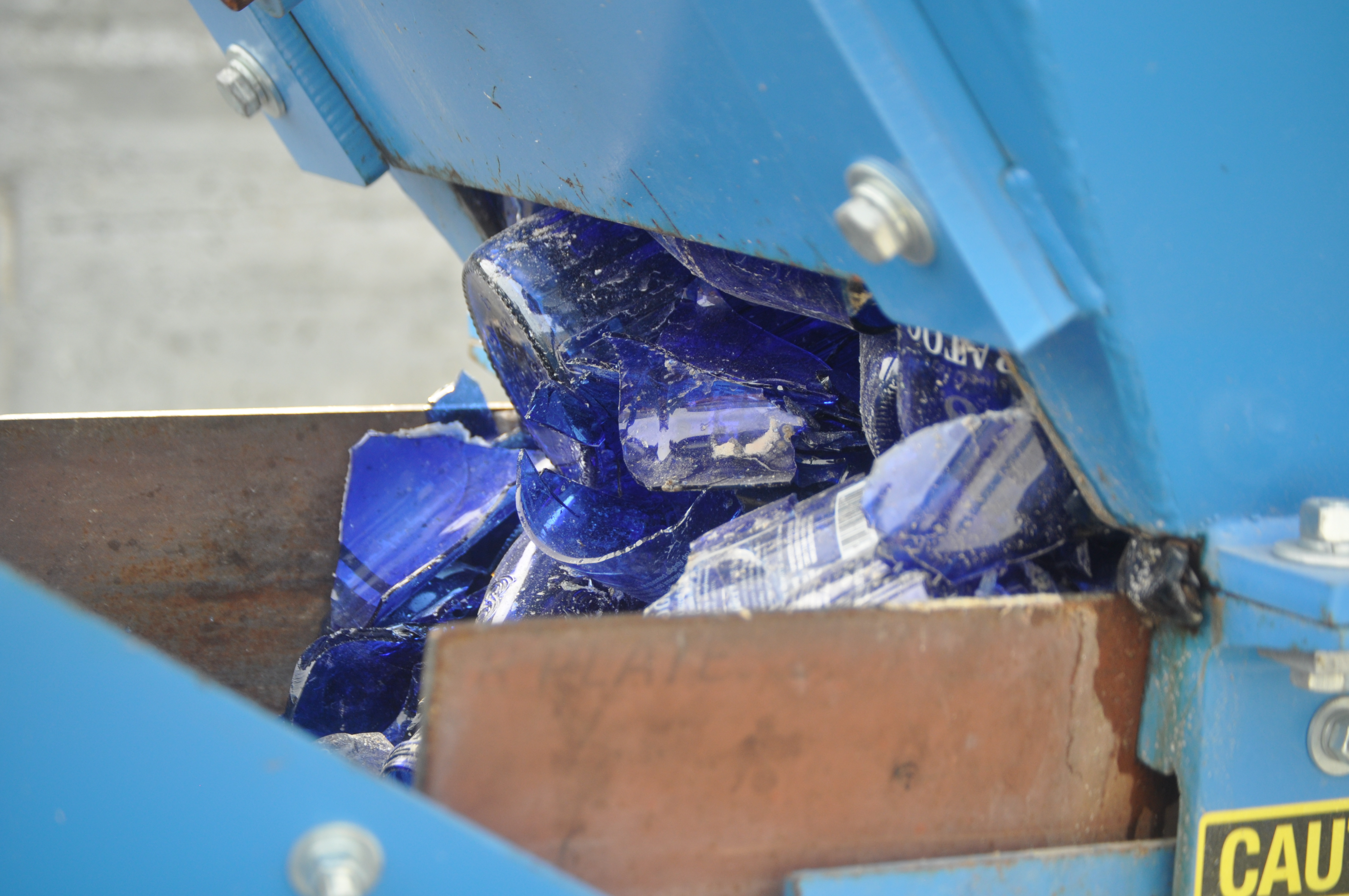 Blue glass bottles entering the crusher